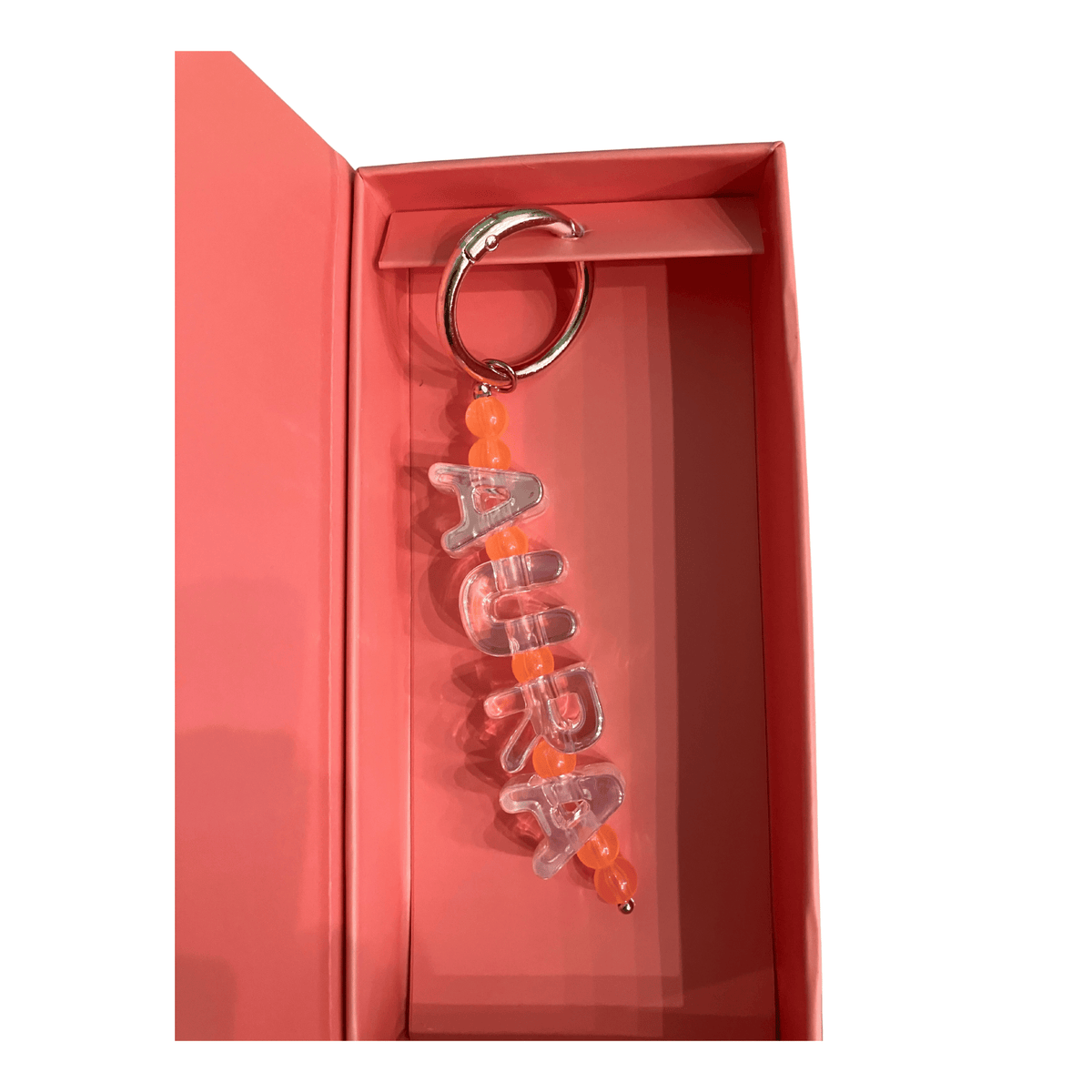 Keychain with 'Alura' branding in a pink box